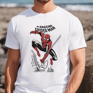 May include: White t-shirt with a red and blue graphic of Spider-Man swinging from a web, with the text "the AMAZING SPIDER-MAN" above him.