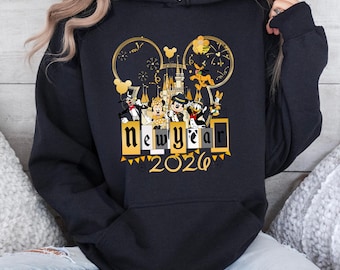 Puede incluir: Sudadera con capucha negra con un diseño de Año Nuevo 2026 con personajes de Disney. El diseño incluye orejas de Mickey Mouse, un castillo, fuegos artificiales y las palabras "New Year" en una fuente decorativa.