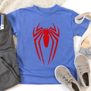 May include: A blue t-shirt with a red spider-man logo on the front.