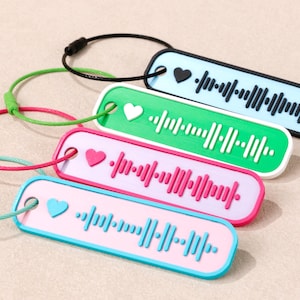 May include: Four keyrings featuring a Spotify code design. Each keyring has a different colour scheme: blue with a black heart, green with a white heart, pink with a pink heart, and light blue with a blue heart. Each has a matching cord.