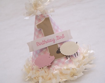 May include: Pink and white gingham party hat with a brown number one, a pink pig, a white sheep, and a white banner that says "Birthday Girl".