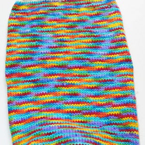 May include: A colorful striped knitted baby sleeper with white straps. The sleeper is made of a soft, comfortable material and is perfect for keeping a baby warm.
