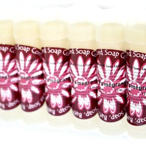 May include: Six white tubes of pomegranate scented soap, each with a red and white flower design and the text "Soap Cord Company" and "Pomegranate" on the label. Each tube is 1.5 oz.