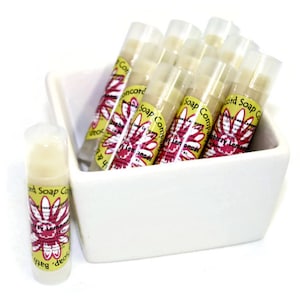 May include: A white ceramic dish filled with multiple clear tubes of lip balm. The tubes have yellow and pink labels with the text "Concord Soap Company" and "Raspberry Lemonade".