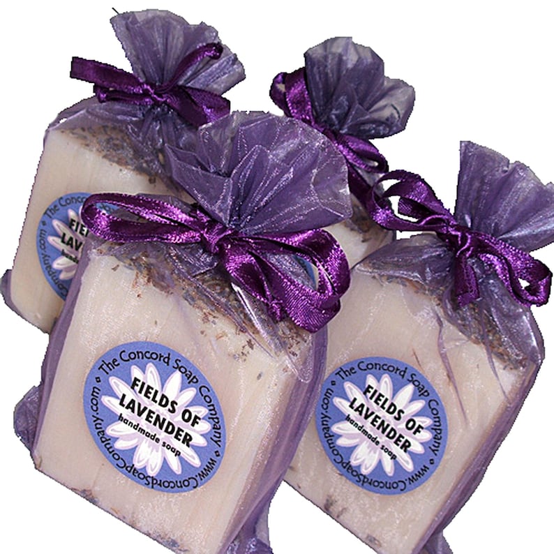 May include: Three bars of handmade lavender soap wrapped in purple sheer fabric with purple ribbon bows. Each bar has a round label that reads 'The Concord Soap Company.com www.ConcordSoapCompany.com FIELDS OF LAVENDER handmade soap'.