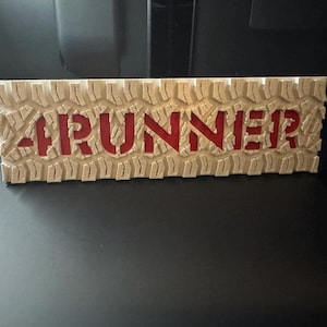 May include: A wooden sign with a tire tread pattern and the word "RUNNER" in red lettering.