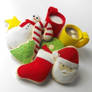 May include: A set of felt Christmas ornaments, including a snowman, a candy cane, a stocking, a gingerbread man, a Christmas tree, and two mugs of hot chocolate.