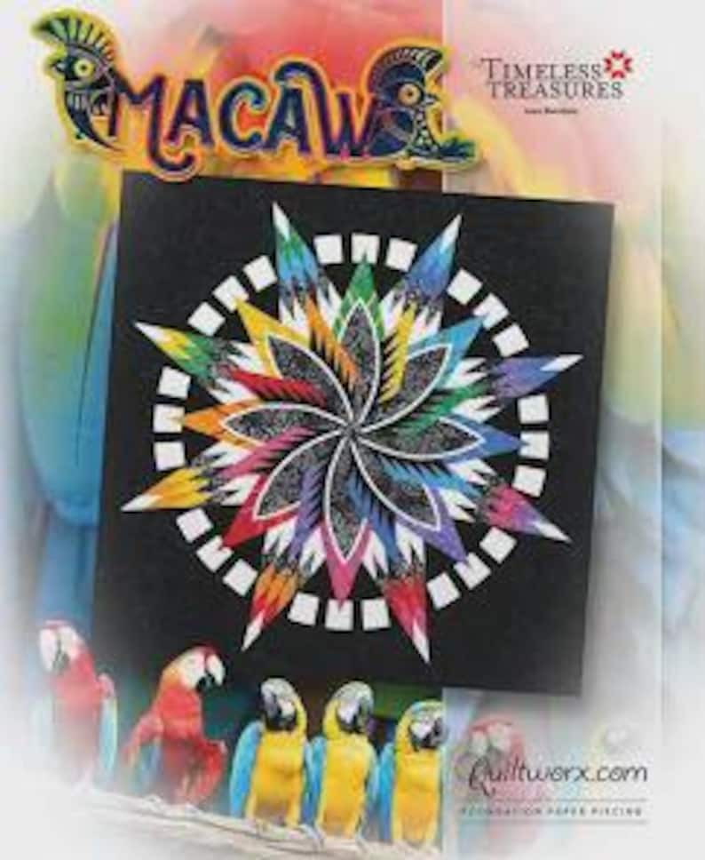 May include: A black square fabric panel with a colorful starburst design, featuring a white circular border. The word "Macaw" is above the panel, with parrot illustrations. The panel is for quilting, with the text "Timeless Treasures" and "Quiltworx.com".