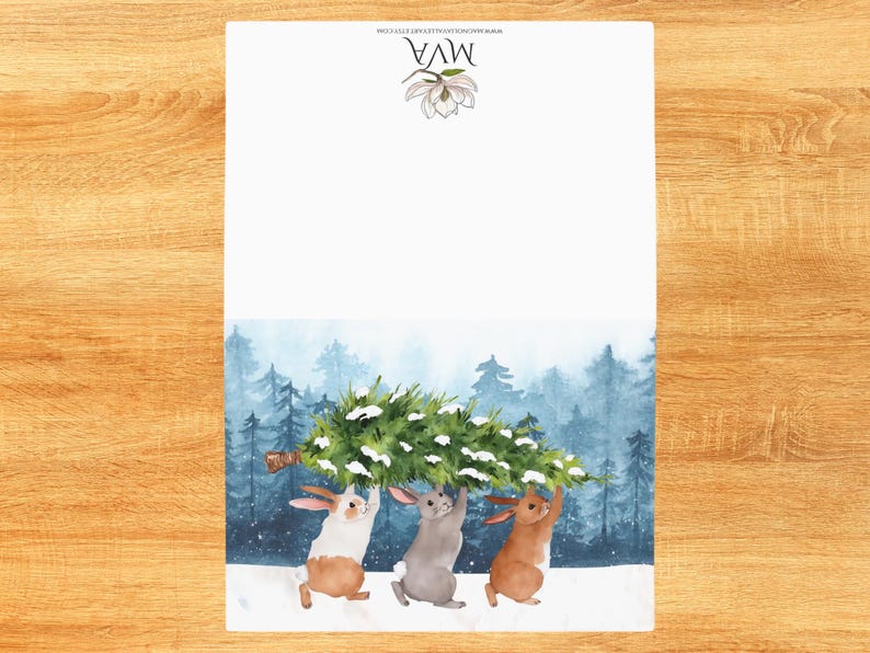 Pode incluir: Ilustra&ccedil;&atilde;o em aquarela de tr&ecirc;s coelhos carregando uma &aacute;rvore de Natal por uma floresta nevada. A parte superior do papel tem o texto "MVA" e um desenho floral. O fundo apresenta uma floresta em aquarela.