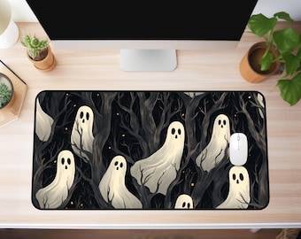 Könnte beinhalten: Rechteckiges Mauspad mit einem gruseligen Halloween-Design. Das Pad zeigt eine dunkle Waldszene mit weißen Geisterfiguren, die zwischen den Bäumen schweben. Eine weiße Computermaus liegt auf dem Pad.