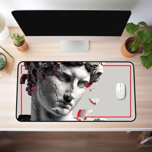 May include: A rectangular mousepad featuring a grayscale illustration of a classical sculpture with red accents. The design includes a cracked effect and a red border. A white mouse is positioned to the right.