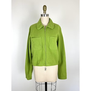 May include: A bright green jacket with a collar, two front pockets, and a full-length zipper. The jacket is displayed on a mannequin. The number "2" is visible on the mannequin.