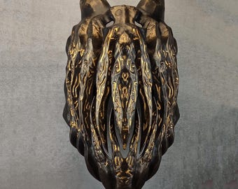 May include: A dark bronze abstract sculpture with gold detailing. The piece features a textured, organic design with a central vertical opening and a shape resembling a stylized animal head. The sculpture is set against a neutral grey background.