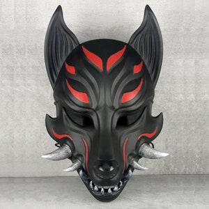 Könnte beinhalten: Eine schwarze Wolfsmaske mit roten Akzenten und silbernen Fangzähnen. Die Maske hat ein detailliertes Design mit spitzen Ohren und einem wilden Ausdruck, geeignet für Cosplay oder Kostümveranstaltungen.