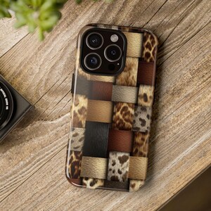 May include: A smartphone case with a patchwork design featuring various animal print patterns in shades of brown, tan, and black. The case has a glossy finish and a camera cutout. The case is on a wooden surface.