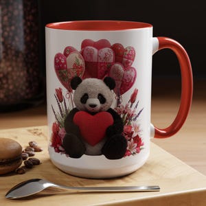 May include: White ceramic mug with a red interior and handle. The mug features a panda holding a red heart, surrounded by floral arrangements and heart-shaped balloons. The design is set against a white background.