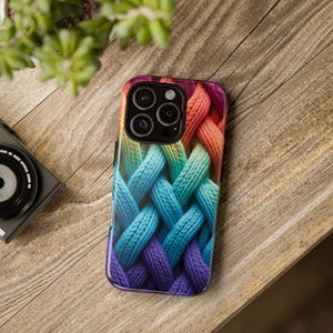 May include: A smartphone case featuring a woven pattern in a gradient of colors, including purple, blue, green, yellow, orange, and pink. The case has a glossy finish and a camera cutout.