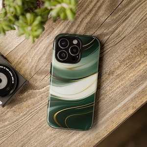 May include: A smartphone case with a green, white, and gold abstract design. The case features a glossy finish with flowing lines and a dark green border. The case is on a wooden surface.