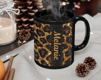 May include: A black coffee mug with a leopard print design in gold and black. The mug has the name "Melanie" printed vertically in gold. Steam rises from the mug, suggesting a hot beverage.