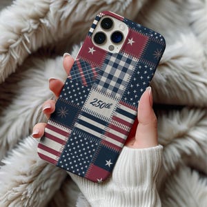 May include: A phone case with a patchwork design featuring red, white, and blue patterns, including stars, stripes, and plaid. The text "250th" is visible on the case. The case is held in a person's hand.
