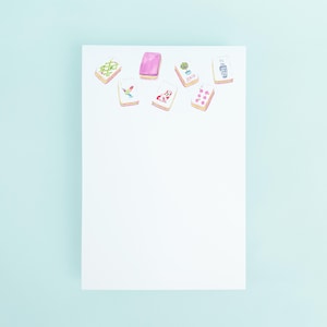 May include: A white sheet of paper with eight colorful rectangular stickers on it. The stickers have various designs, including a hummingbird, a plant, a heart, and a geometric pattern.