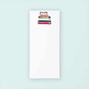 May include: A white notepad with a stack of books and a pair of glasses on top. The books are red, green, blue, and white.