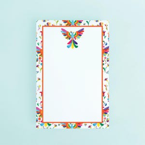 May include: A rectangular notepad with a white background, featuring a colorful border and a central image of a stylized bird. The border includes floral and bird motifs in various colors, with an orange inner frame.