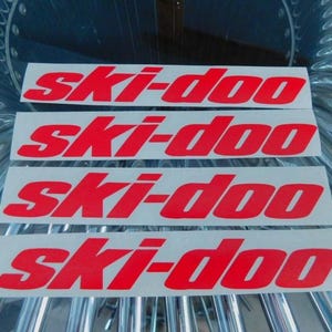 May include: Four white stickers with the red text "ski-doo" repeated on each sticker.