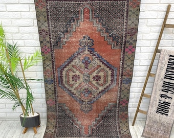 May include: A vintage rug with a faded orange background and a geometric pattern in shades of blue, green, and red. The rug has a distressed look and is perfect for adding a touch of bohemian style to your home.