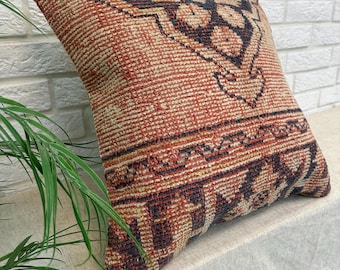 May include: A square throw pillow featuring a woven texture with a geometric pattern in shades of terracotta, cream, and dark charcoal. The design includes intricate angular lines and repeating motifs across the front surface of the cushion.