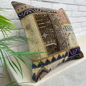 May include: A decorative pillow with a patchwork design. The pillow features a variety of colors, including brown, beige, blue, and pink. The pillow has a textured appearance and is likely made of fabric. The pillow is rectangular and appears to be well-made.