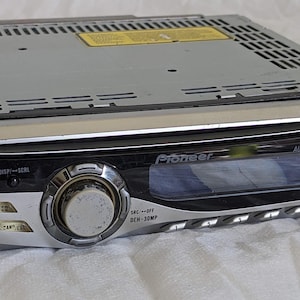 Könnte beinhalten: Ein silber-schwarzes Pioneer DEH-30MP Autoradio mit zentralem Lautstärkeregler, digitalem Display und verschiedenen Bedientasten. Das Gerät verfügt über einen integrierten CD-Schacht, einen AUX-Eingang sowie WMA- und MP3-Wiedergabefunktion.
