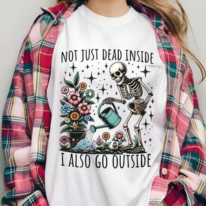 Pode incluir: Camiseta branca com um esqueleto regando flores e o texto "Not just dead inside I also go outside".