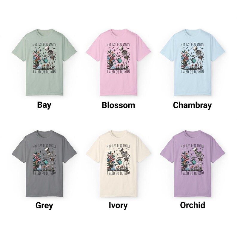 Pode incluir: Seis t-shirts de diferentes cores com um esqueleto a regar uma planta e o texto "Not just dead inside I also go outside". As cores s&atilde;o ba&iacute;a, flor, chambray, cinza, marfim e orqu&iacute;dea.