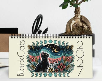 Könnte beinhalten: Ein spiralgebundener Tischkalender mit dem Titel Black Cats 2027, der eine zentrale Illustration einer schwarzen Katze zeigt, die in einen Sternenhimmel mit Mondsichel blickt, umgeben von bunten Blumen, Blättern und einer Mondphasen-Bordüre.