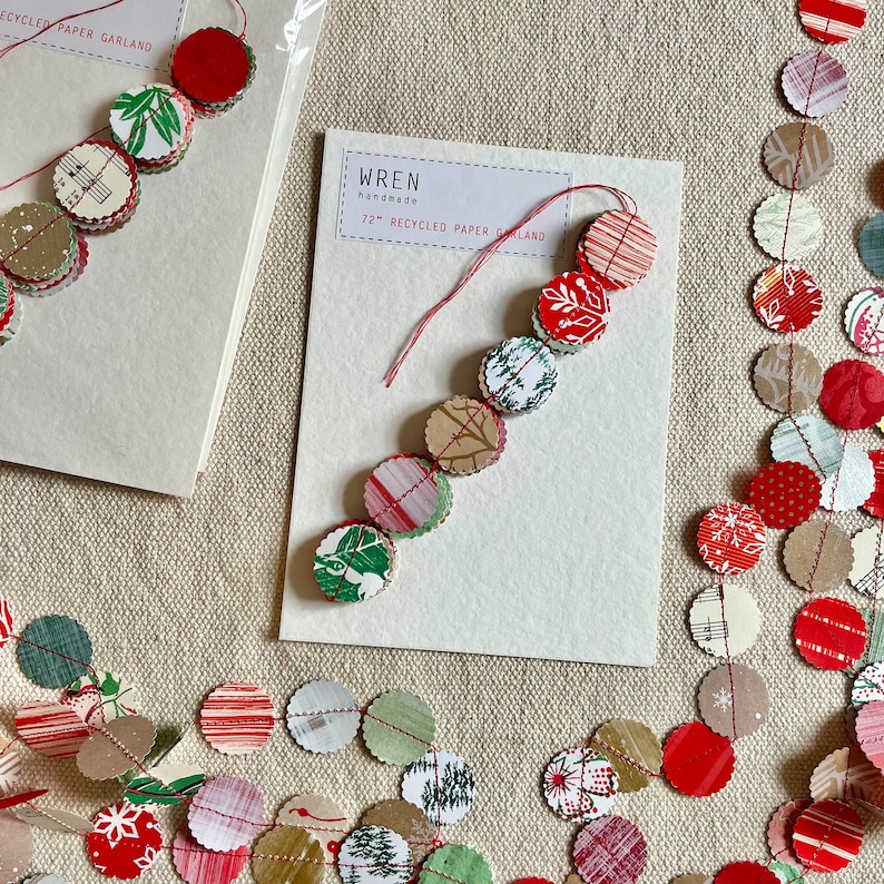 May include: A red and green paper garland with a white card that reads "WREN handmade 72" recycled paper garland".