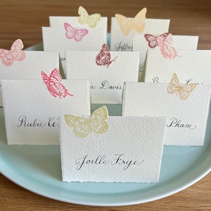 May include: Place cards with butterfly designs and handwritten names, including "Joelle Frye", "Rubie C", "Pham", and "Eric Davis".