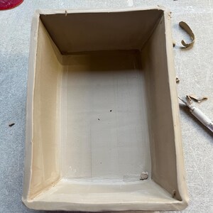 K&ouml;nnte beinhalten: Eine rechteckige Keramikbox mit hellbraunem &Uuml;berzug. Die Box ist leer und hat eine glatte, leicht strukturierte Oberfl&auml;che.