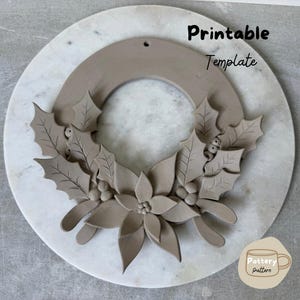 May include: A circular clay wreath ornament featuring sculpted holly leaves, berries, and a central poinsettia flower. The text "Printable Template" is visible at the top, and a small logo with the text "Pottery Pattern" is in the bottom right corner.