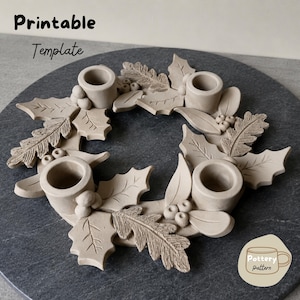 Puede incluir: Un portavelas circular de arcilla beige con cuatro copas cilíndricas dispuestas en forma de corona. La superficie está decorada con hojas de acebo, hojas de roble y pequeños racimos de bayas esculpidos. El texto dice Printable Template y Pottery pattern.