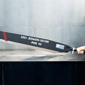 May include: A black and silver sword with a red stripe and the text "2321. S514476-35/UN POS 53" on the blade.