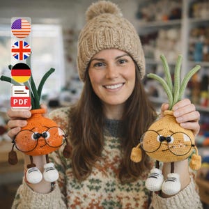 May include: Two crocheted onion dolls with glasses, arms, and legs are held up by a person. The dolls are orange and yellow with green tops. The person is wearing a beige knit hat and a patterned sweater.