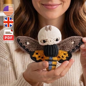 May include: A crocheted moth with a cream-colored head, black eyes, and brown and yellow wings. The moth has a black body and blue and yellow stripes. The image includes a PDF icon and flags for the United States and the United Kingdom.