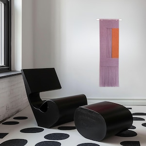 Könnte beinhalten: Ein modernes Interieur mit einem schwarzen Stuhl und Hocker-Set auf einem schwarz-weiß gemusterten Boden. Ein dekorativer Wandbehang mit lila und orangefarbenen Akzenten wird gezeigt. Ein Fenster ist im Hintergrund zu sehen.