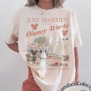 Pu&ograve; includere: T-shirt color avorio con tema matrimonio a Disney World. La maglietta presenta la scritta "Just Married Disney World Est 2026" con Topolino e Minnie, un castello e fuochi d'artificio. La maglietta &egrave; del marchio Comfort Colors.