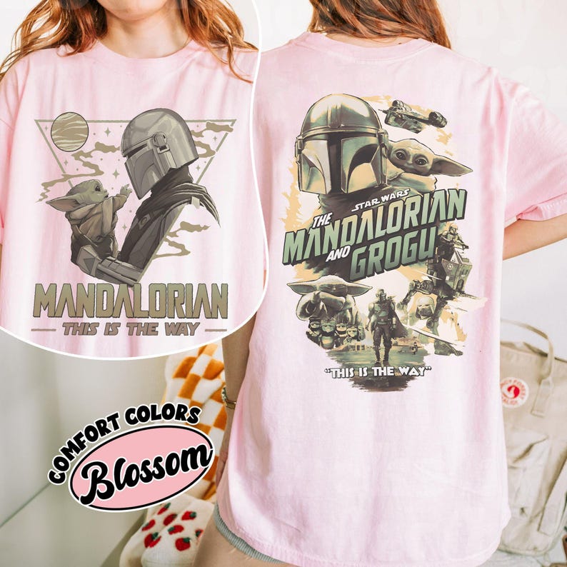 Op de afbeelding: Zachtroze T-shirt met een afbeelding van The Mandalorian en Grogu. Het ontwerp aan de voorkant toont de Mandalorian en Grogu met de tekst "MANDALORIAN - THIS IS THE WAY". Het ontwerp aan de achterkant bevat het Star Wars logo en meer karakters.