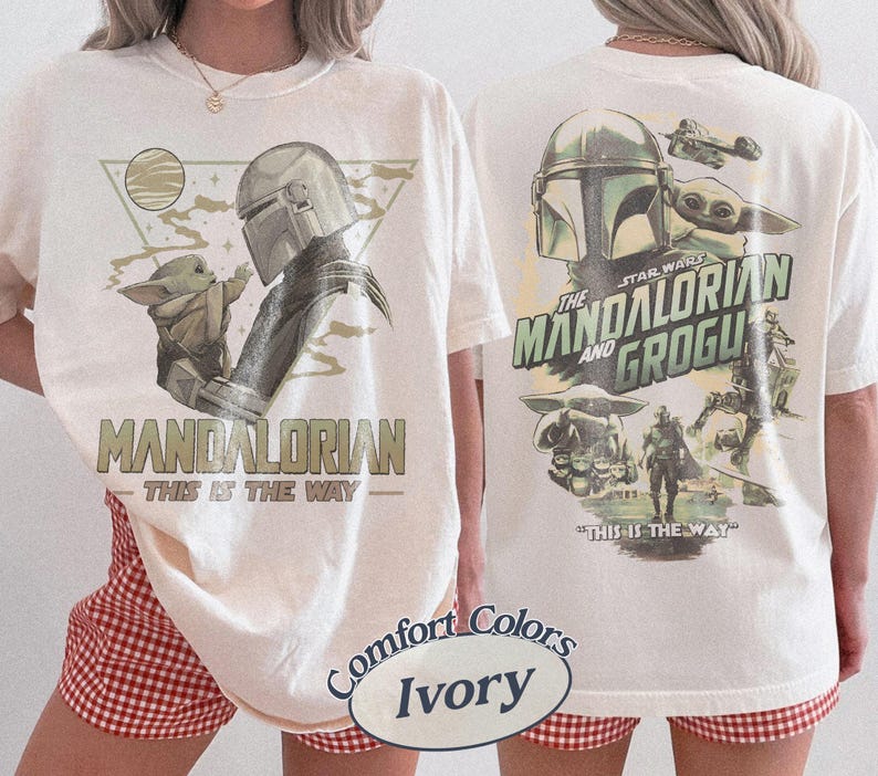 Op de afbeelding: Ivoor kleurig t-shirt met een afbeelding van The Mandalorian en Grogu. De voorkant toont "MANDALORIAN" en "THIS IS THE WAY." De achterkant toont "THE STAR WARS MANDALORIAN AND GROGU" met extra afbeeldingen.