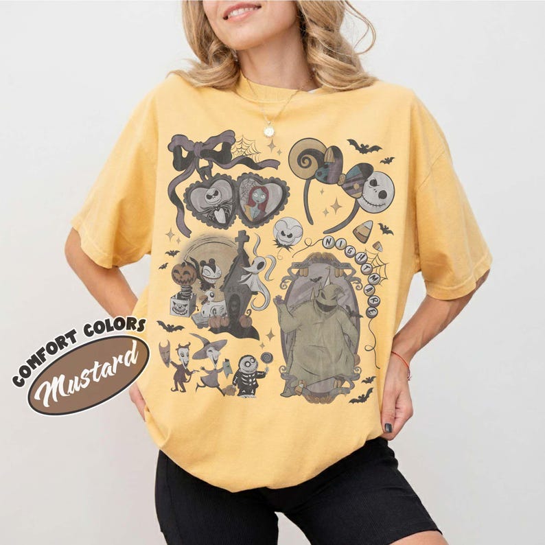 May include: A mustard yellow short-sleeve t-shirt featuring a graphic print of characters and motifs from The Nightmare Before Christmas, including Jack Skellington, Sally, Oogie Boogie, and a pair of mouse ears, with the text COMFORT COLORS MUSTARD.
