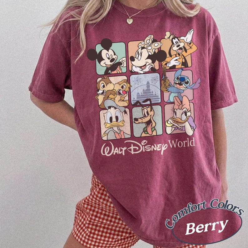 May include: Berry-colored t-shirt featuring a grid of Disney characters including Mickey Mouse, Minnie Mouse, and Goofy. The shirt has the words "Walt Disney World" printed below the grid. The shirt is labeled "Comfort Colors Berry".