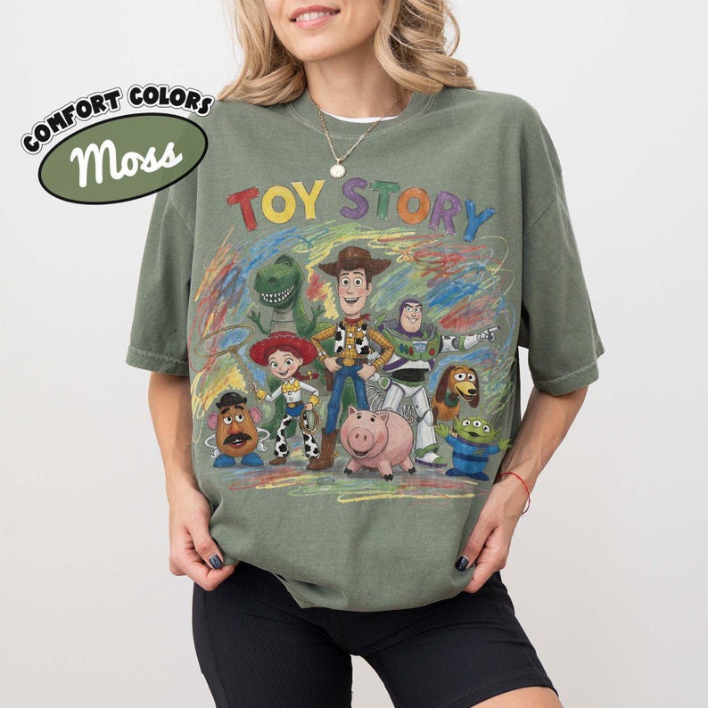 Pu&ograve; includere: Una t-shirt a maniche corte color verde muschio con una stampa grafica colorata dei personaggi di Toy Story, tra cui Woody, Buzz Lightyear, Jessie, Rex, Hamm, Mr. Potato Head e Slinky Dog. Il testo TOY STORY &egrave; stampato in lettere multicolori.